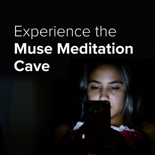 Experience the Muse Meditation Cave — person lit by phone screen, looking down in dark