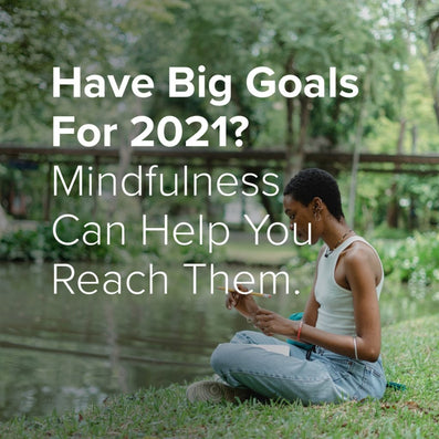 Person seated by a pond; overlaid text reads: Have Big Goals For 2021? Mindfulness Can Help You Reach Them.