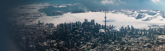 Aerial view of Toronto skyline with CN Tower and ice-covered harbor under winter sunlight.
