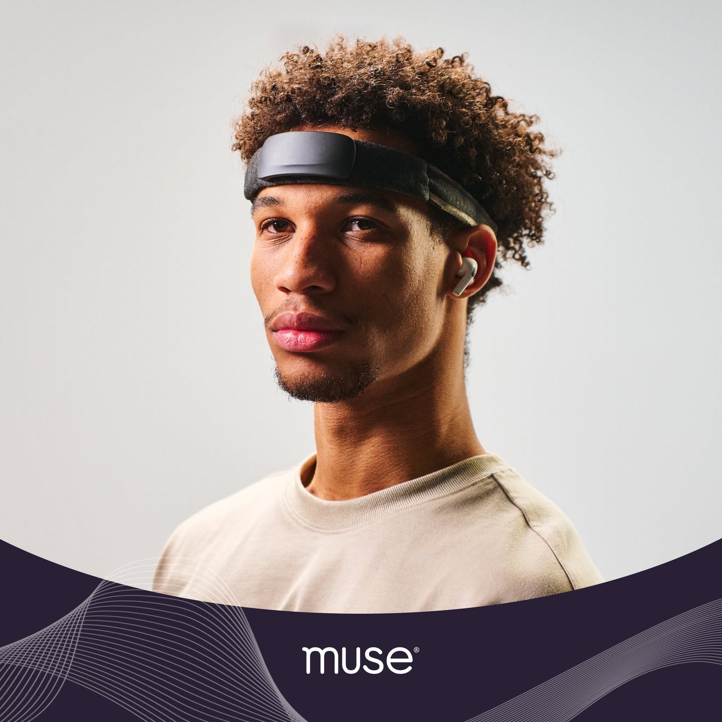 Young man wearing a Muse brain-sensing headband and a wireless earbud, three-quarter portrait; 'muse' logo visible.