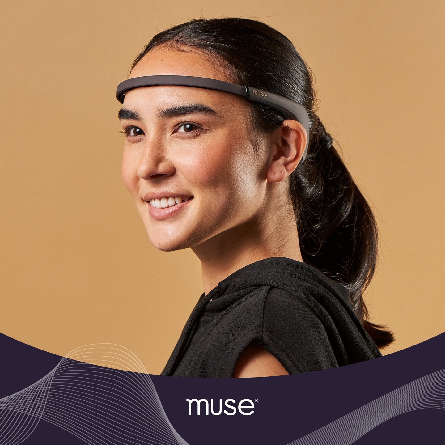 Smiling woman in a hoodie wearing a muse headband across her forehead, side portrait on beige background, muse logo visible