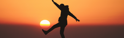 Silhouette of a person balancing on one leg at sunset, symbolizing work–life balance