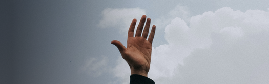 Raised hand reaching toward a cloudy sky, evoking support and hope for mental health awareness.