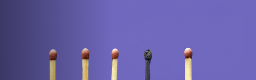 Five vertical matchsticks on purple background; center match completely charred while the others remain unlit with red tips.