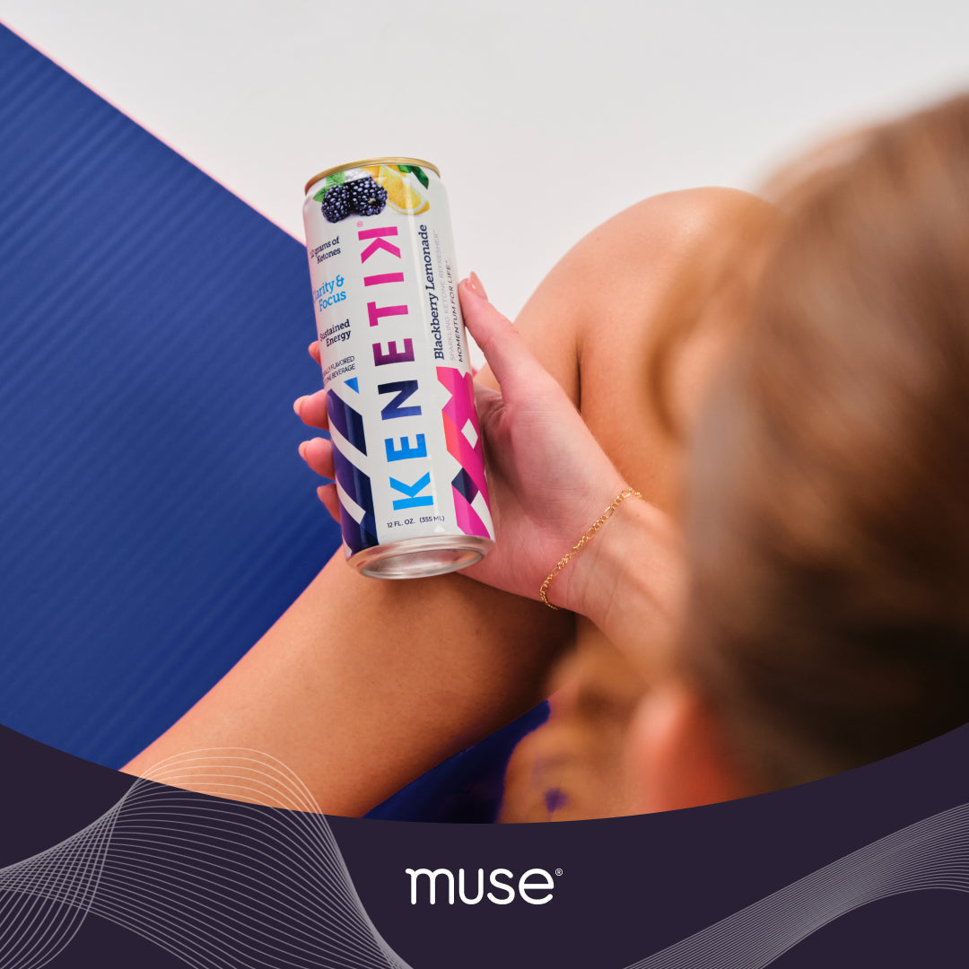 Person holding a Kenetik blackberry lemonade ketone drink can while seated on a blue exercise mat, Muse logo overlaid at bottom