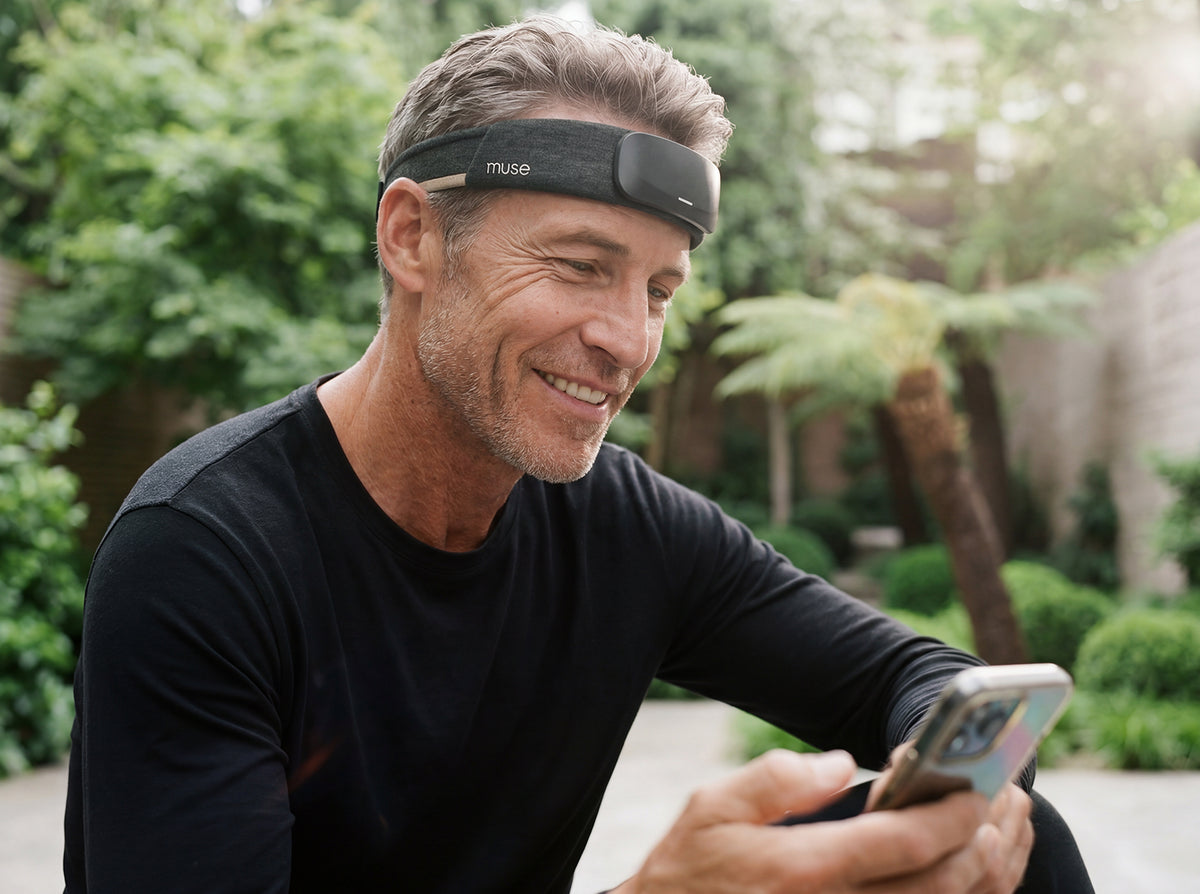 Man wearing a Muse S headband and looking at his phone outdoors