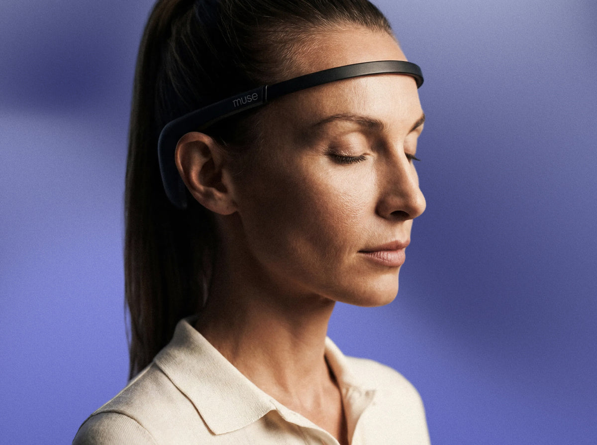 Woman wearing a Muse headband with eyes closed against a purple background