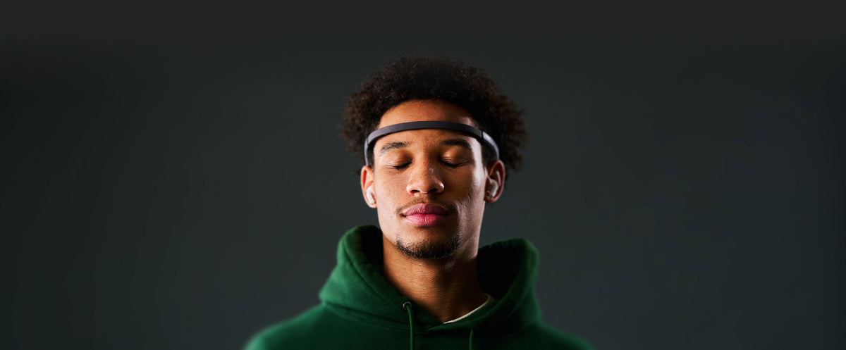 Man wearing a black Muse 2 headband, eyes closed, against a dark background